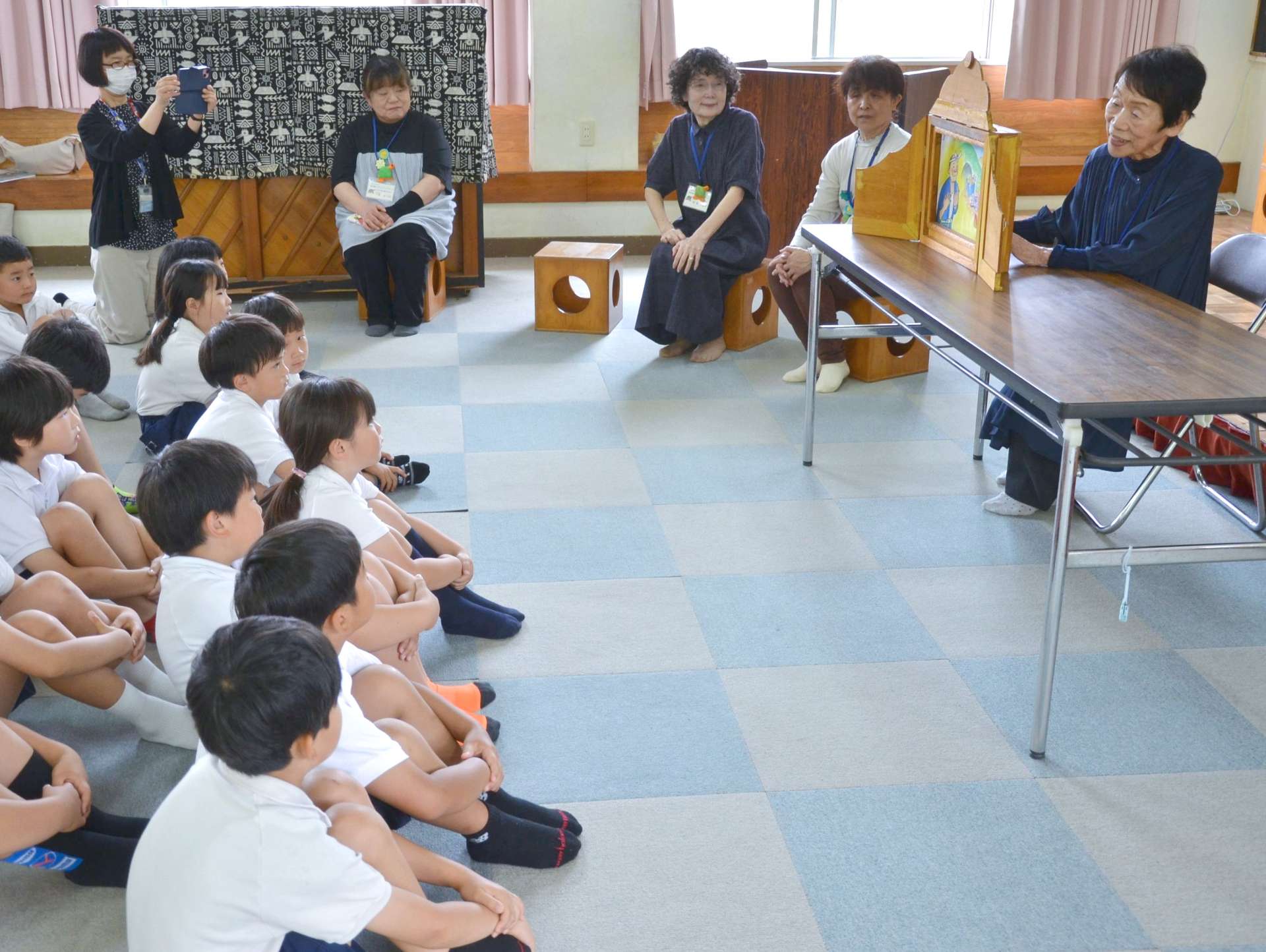 紙芝居を披露する福宿玲子さん（右）ら「こけけ読み聞かせたい」の会員＝日置市東市来の伊作田小学校