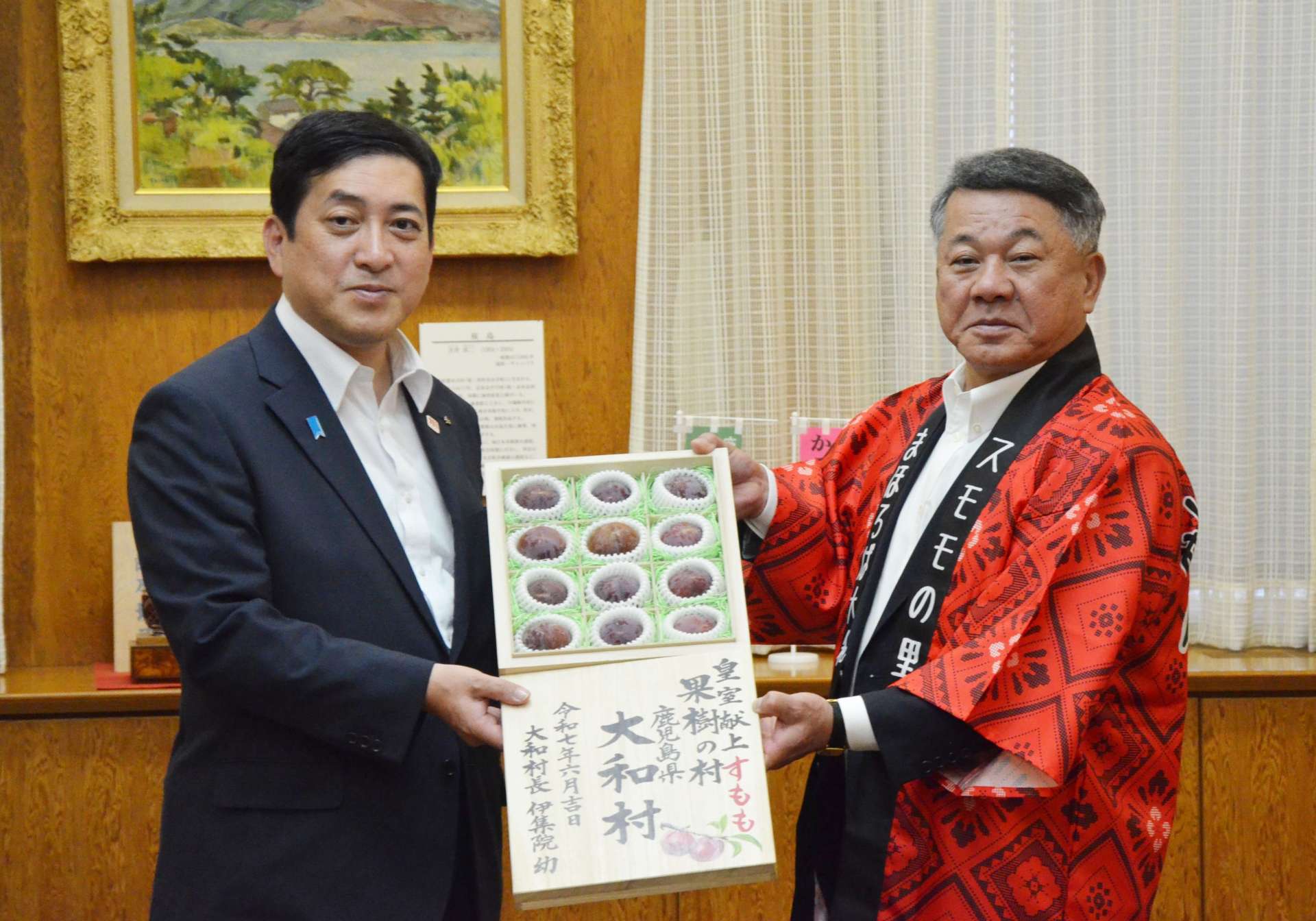 収穫シーズンを迎えた奄美プラムを受け取る塩田康一知事（左）＝２日、県庁