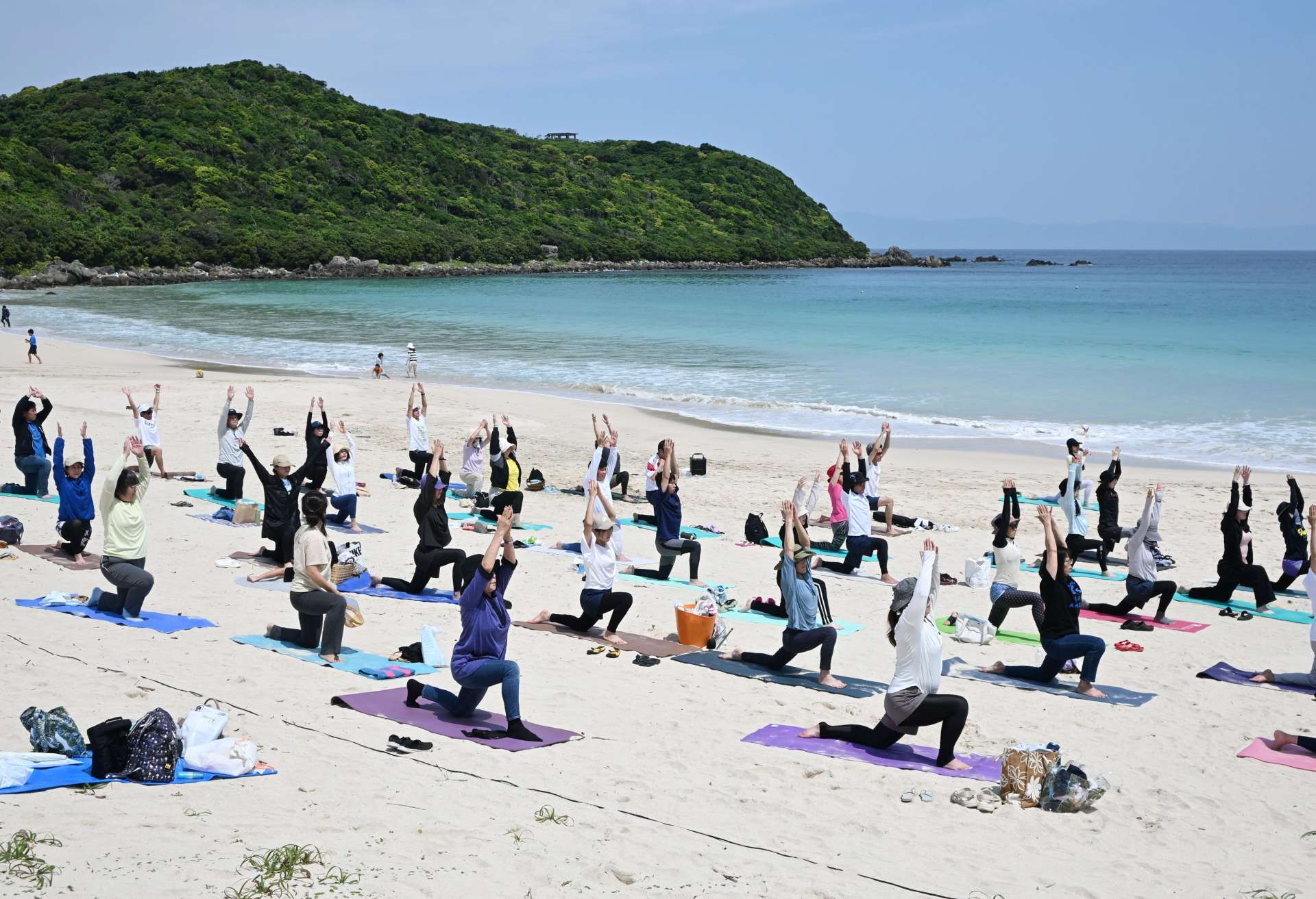 波の音を聞きながらヨガをする参加者＝１日、西之表市国上の浦田海水浴場
