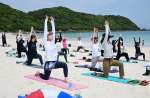 波の音を聞きながらヨガをする参加者＝西之表市国上の浦田海水浴場