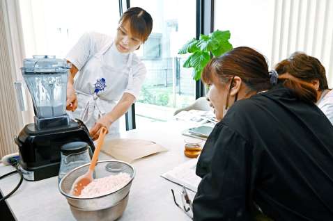 生米をミキサーにかける手順を教える吉峰明子さん＝南さつま市加世田