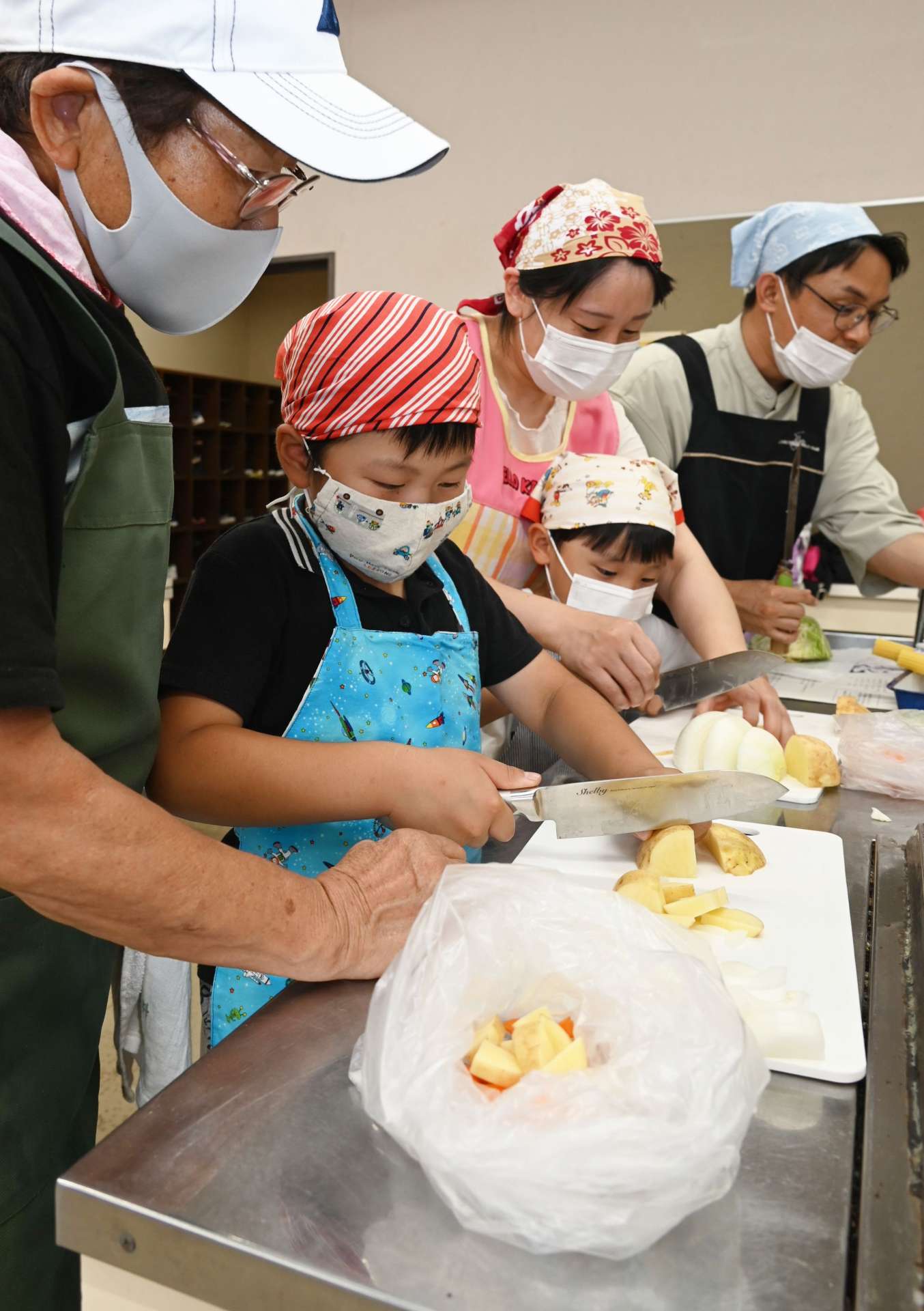 ポリ袋（手前）に入れる材料を切る児童ら＝南さつま市民センター