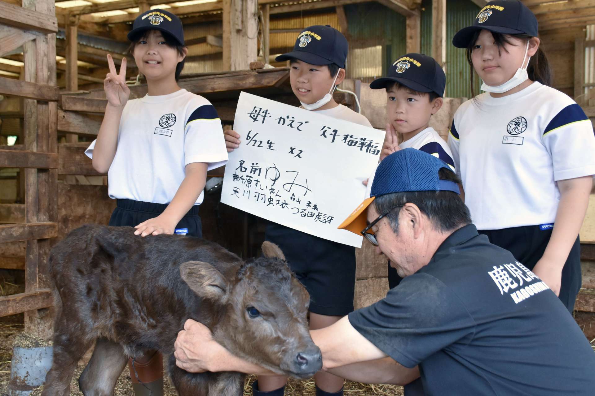 名前を付けた子牛と記念写真を撮る牧之原小の児童＝霧島市福山町福地の長浜牧場