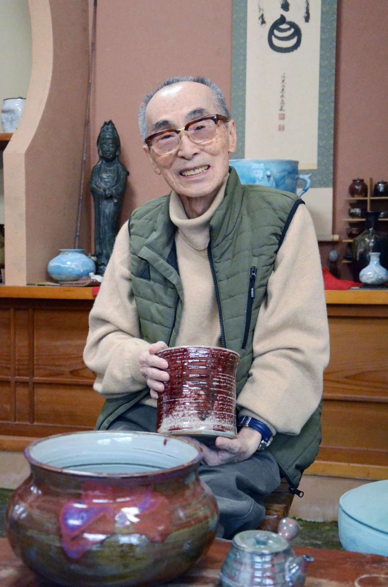市役所レリーフに使われた、緑や赤に発色する辰砂釉について語る有山長佑さん＝２０２５年４月、鹿児島市下福元町