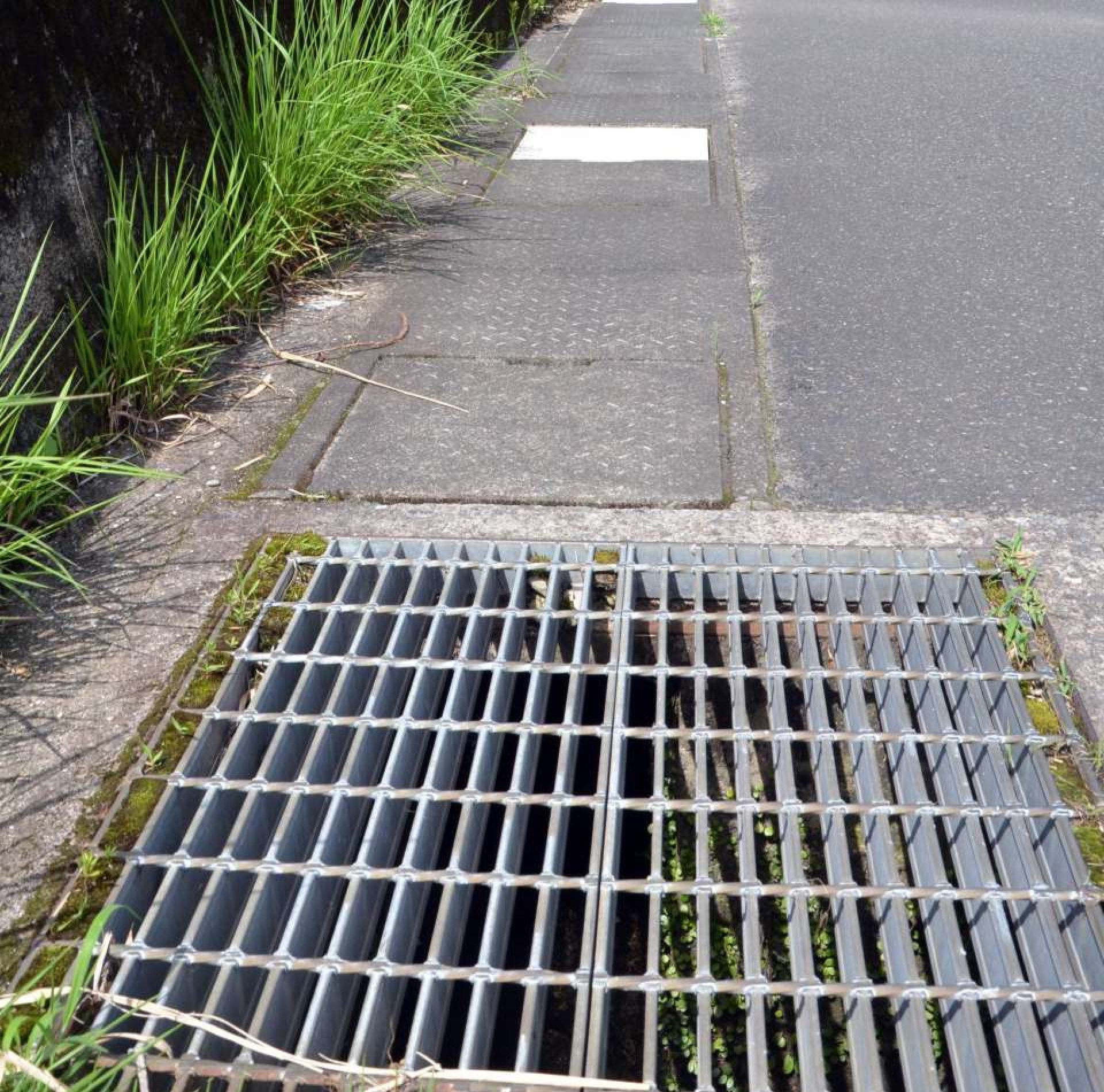 手前は鉄製のグレーチング。奥の白いふたは補修のため新調したコンクリート製＝６月１８日、鹿児島市西別府町