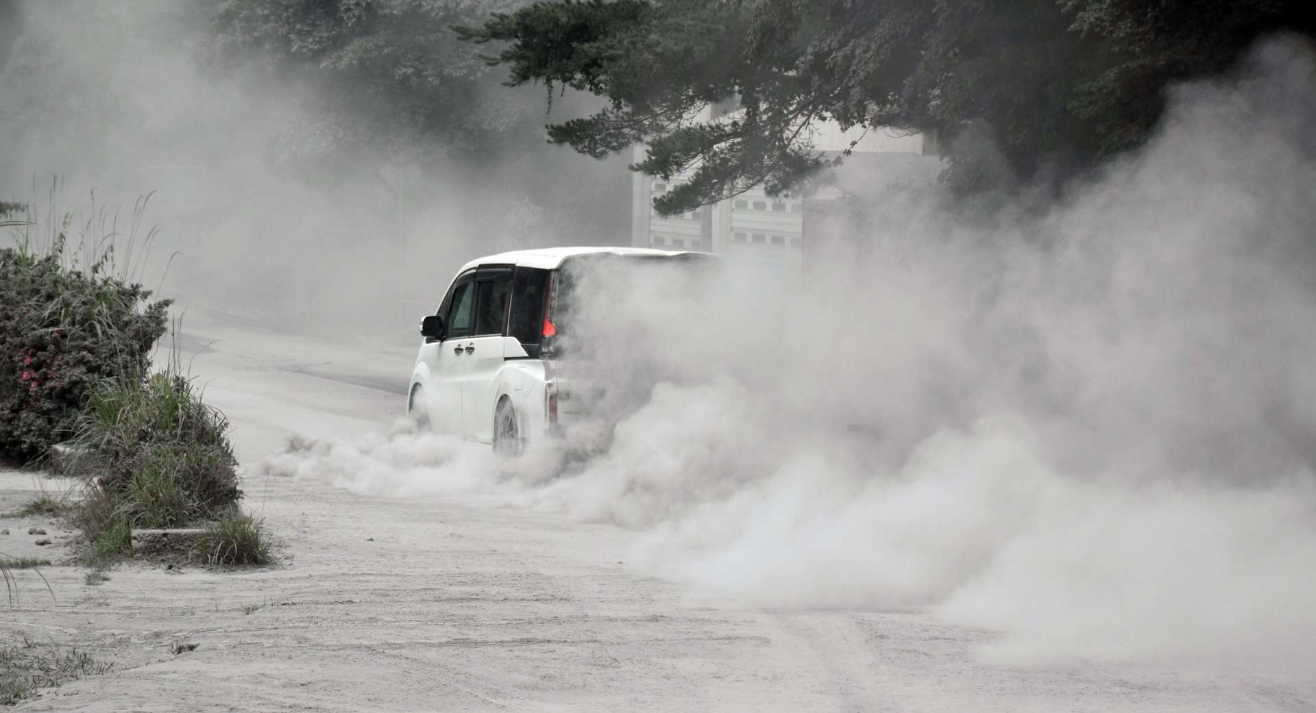 〈まるで砂漠のラリーカー〉火山灰を巻き上げながら走る車＝４日午後０時２５分ごろ、霧島市牧園町高千穂の県道