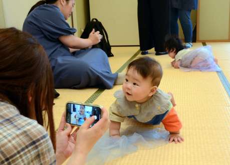 〈笑って。ねえ、笑って〉赤ちゃんのベストショットを撮ろうと奮闘する参加者＝鹿児島市東部親子つどいの広場なかまっち
