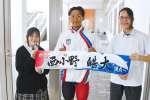 競泳の世界選手権に出場する西小野皓大選手（中京大、中央）。母校の鹿児島情報高校の生徒がデザインしたタオルを手に世界に挑む