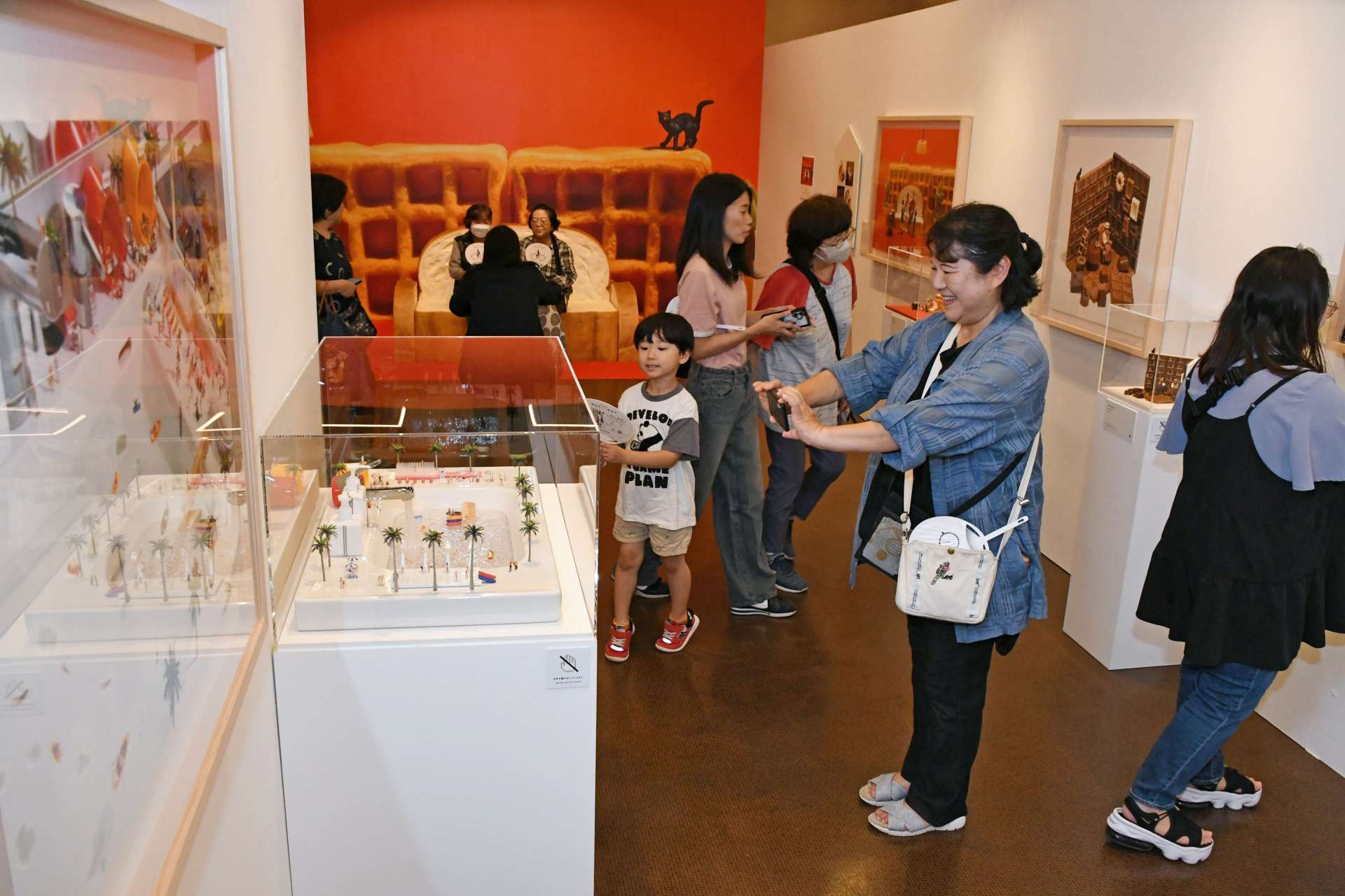田中達也さんの「見立ての世界」を楽しみながら鑑賞する来場者＝４日、鹿児島市の黎明館