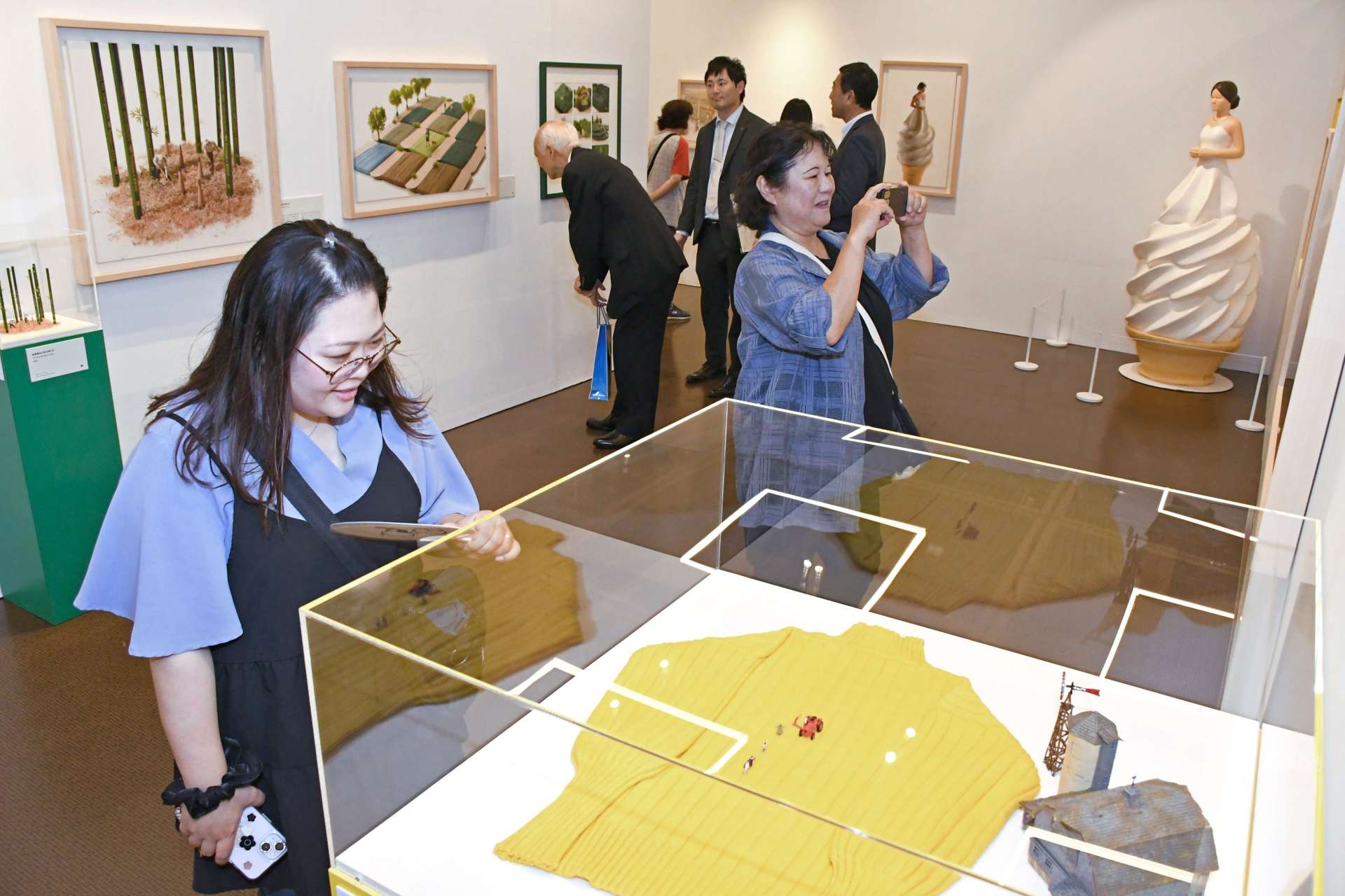 田中達也さんの「見立ての世界」を楽しみながら鑑賞する来場者＝４日、鹿児島市の黎明館