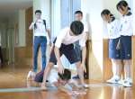 〈これがコツ〉雑巾がけリレーのコツを鹿児島女子高生に伝授する楠隼高生＝肝付町の楠隼中高一貫校
