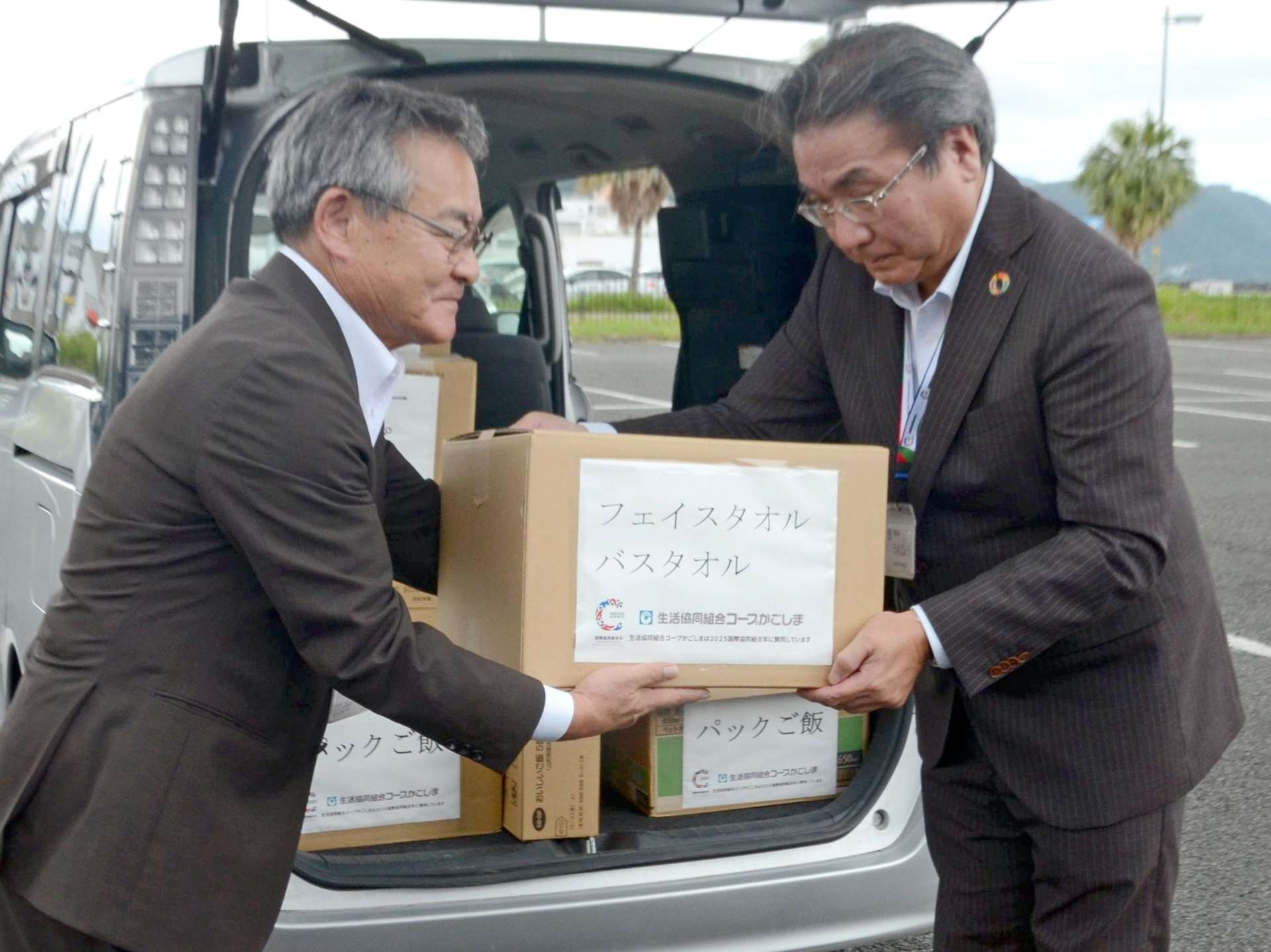 コープかごしまの上城秀人理事長（右）より支援物資を受け取る十島村の久保源一郎村長（左）＝１１日、鹿児島市の鹿児島本港新町の南ふ頭
