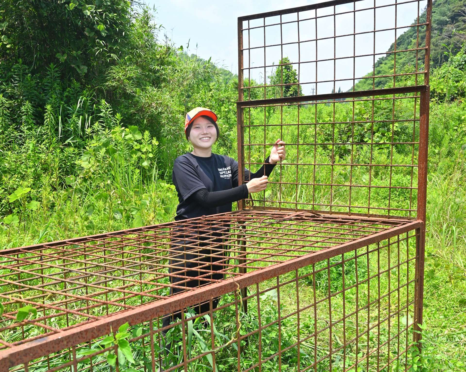 〈関連〉わなの点検をしながら笑顔を見せる外山千乃さん＝鹿児島市犬迫町