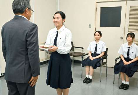 〈十島村〉への支援品を久保源一郎村長に手渡す鹿児島女子高生＝１８日、鹿児島市泉町の同村役場