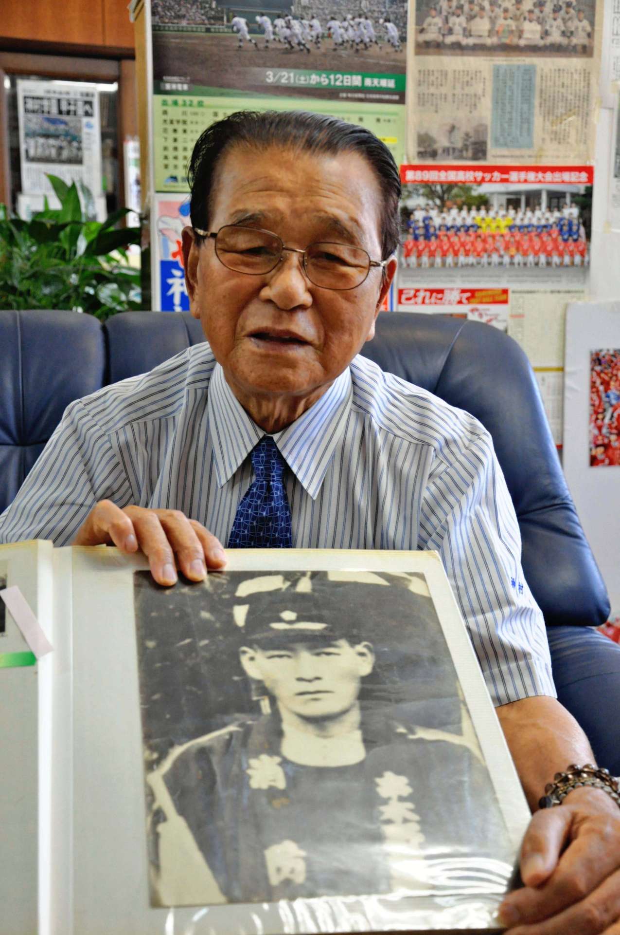 父・栄助さんの遺影を手に「苦しんでいる父に何もしてやれなかった」と振り返る神村勲さん＝いちき串木野市の神村学園