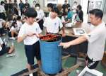 巣を遠心分離機にかけてハンドルを回す生徒たち＝出水市の野田中学校