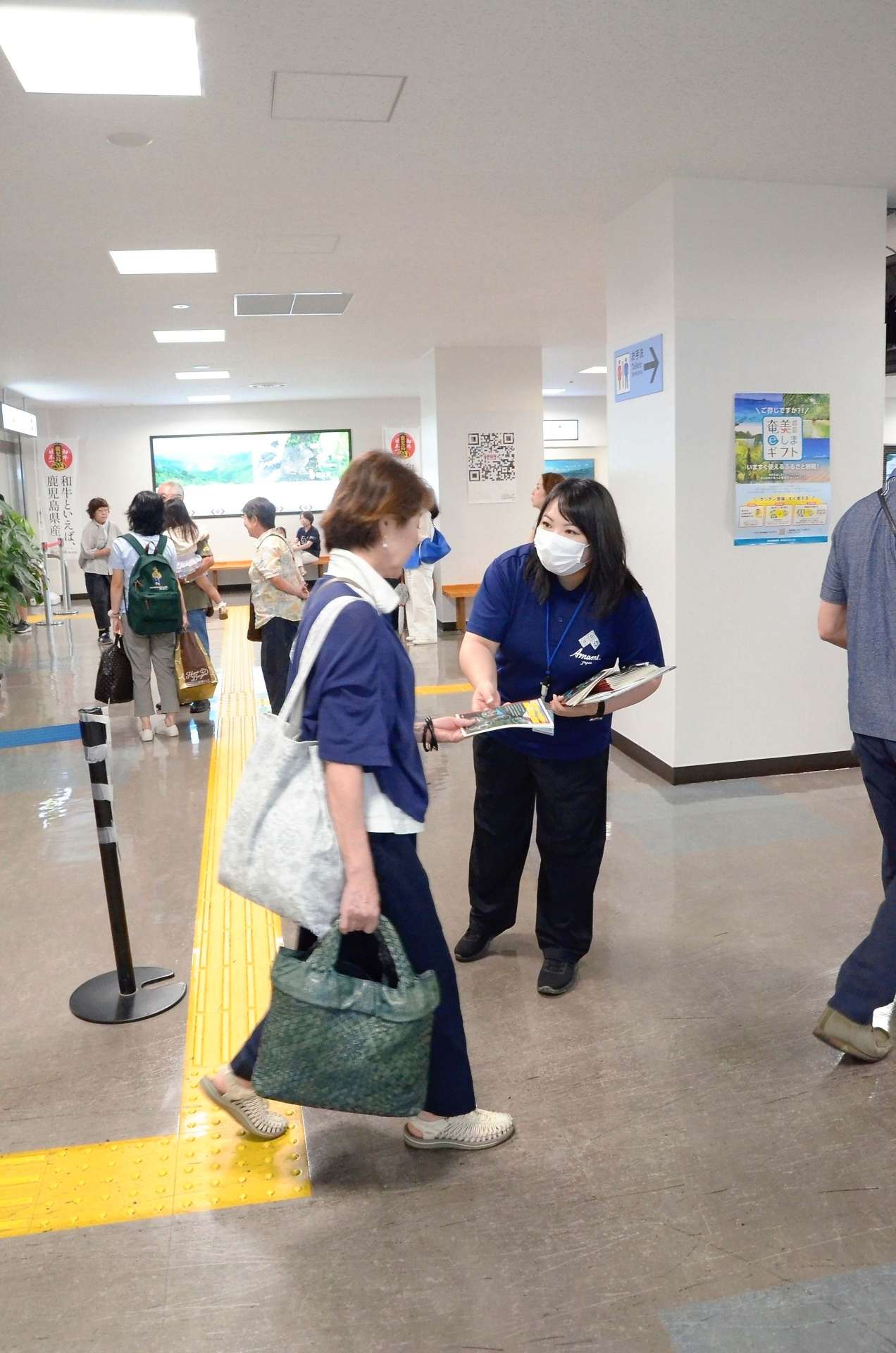 来島者にチラシを手渡す神田あんずさん＝１９日、奄美市笠利の奄美空港