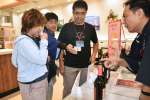 中国人観光客に鹿児島県産焼酎の試飲を勧める浜田酒造社員ら＝霧島市の鹿児島空港国際線ターミナル