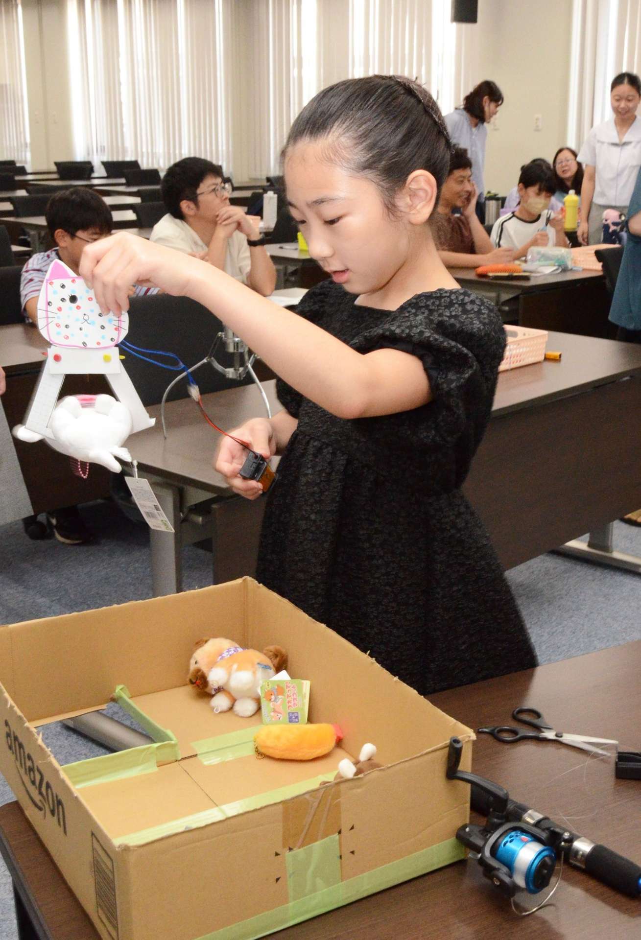 自作の「ＵＦＯメカ」でぬいぐるみを持ち上げる小学生＝鹿児島市郡元２丁目の鹿児島大学