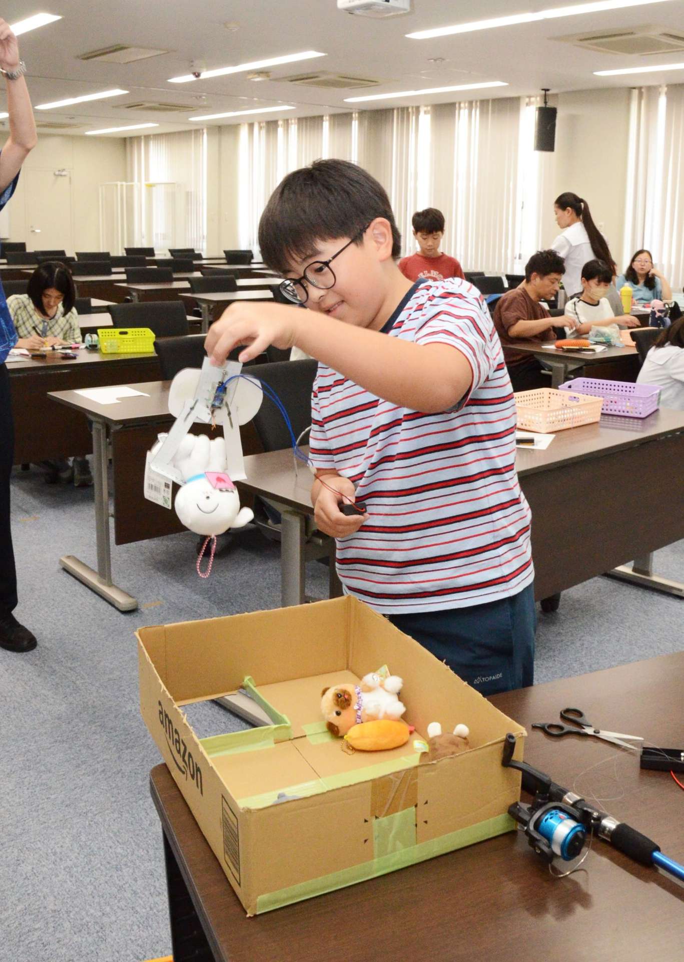 自作の「ＵＦＯメカ」でぬいぐるみを持ち上げる小学生＝鹿児島市郡元２丁目の鹿児島大学