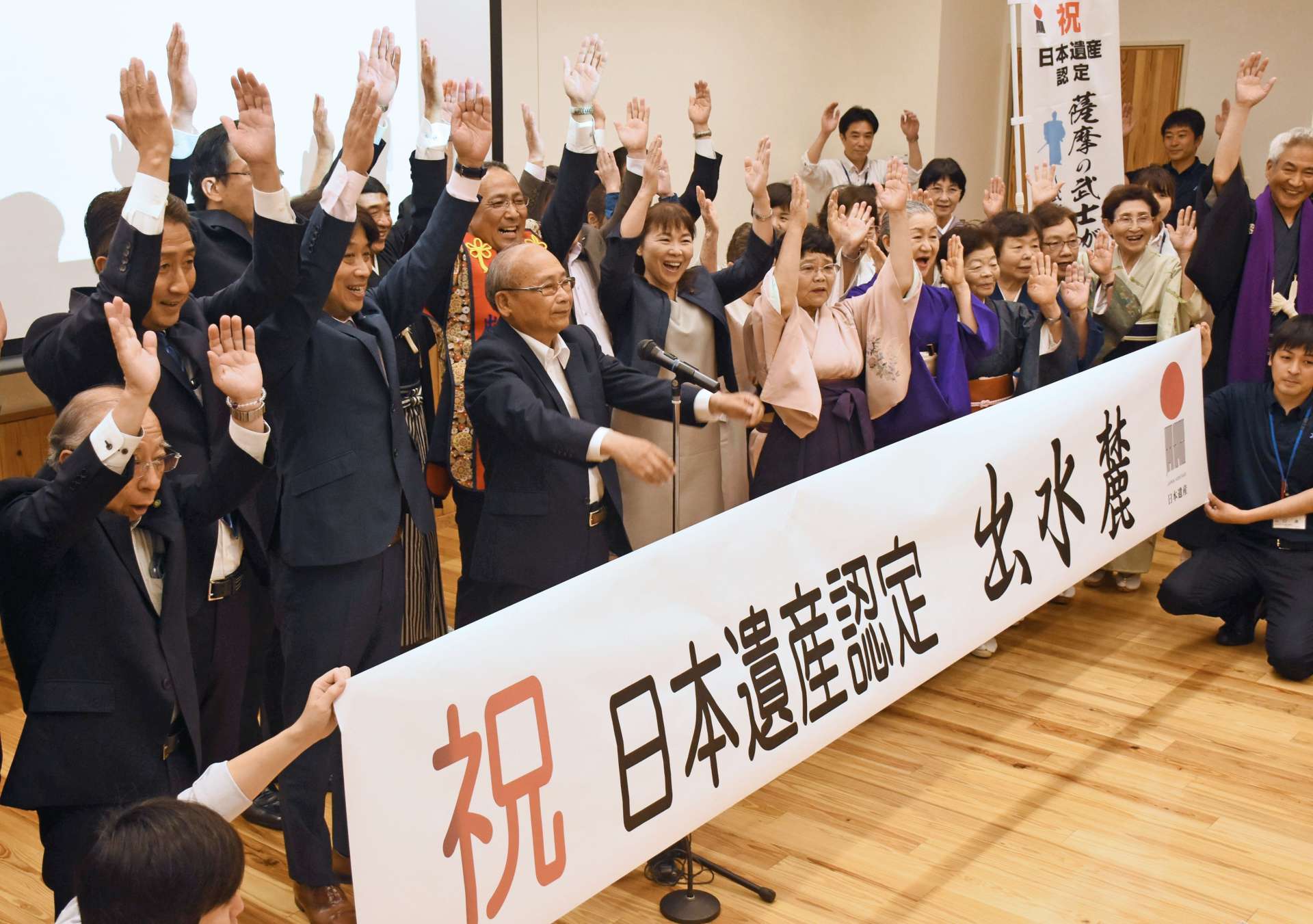 〈資料写真〉２０１９年５月、日本遺産認定に万歳で喜ぶ出水市の関係者ら＝出水市役所