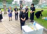 鹿児島大空襲の犠牲となった学友に献花する松田正子さん（中央）＝６月１７日、鹿児島市中央町の共研公園