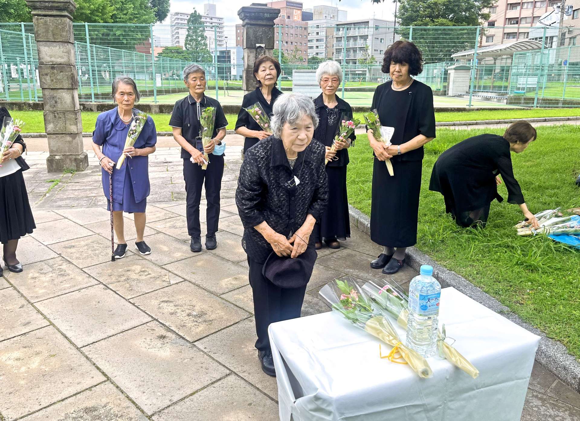 鹿児島大空襲の犠牲となった学友に献花する松田正子さん（中央）＝６月１７日、鹿児島市中央町の共研公園