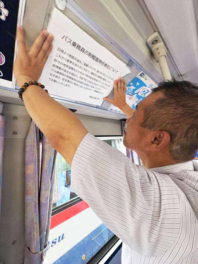 熱中症対策で、脱帽による運転のお知らせを張る南国交通の社員＝鹿児島市の同社鹿児島営業所