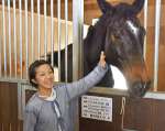 馬と触れ合う石黒櫻さん＝曽於市財部の南九州畜産獣医学拠点