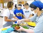 鶏飯を提供するスクールソーシャルワーカー（右）＝奄美市名瀬の金久中学校