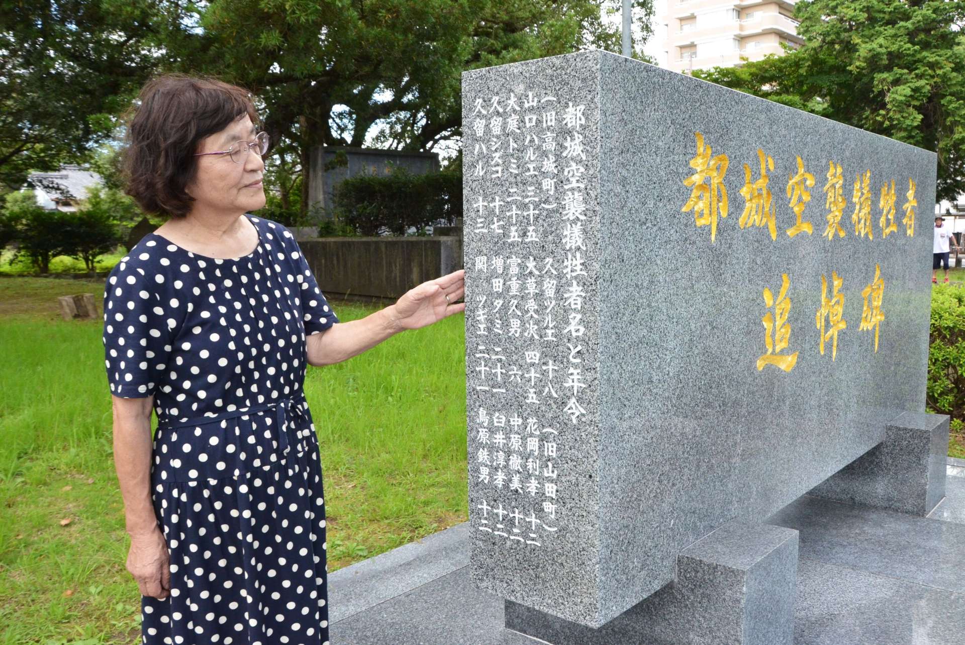 「都城空襲犠牲者追悼碑」の側面に新たに刻まれた犠牲者１３柱と刻字を提案した来住ケイ子さん＝都城市小松原町