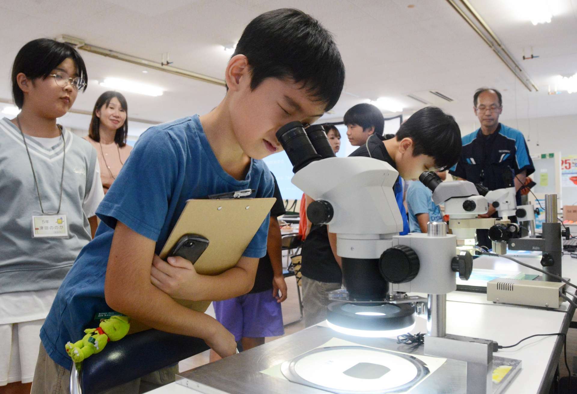 顕微鏡で観察する小学生＝日置市のレゾナック・オプトエレクトロニクス鹿児島