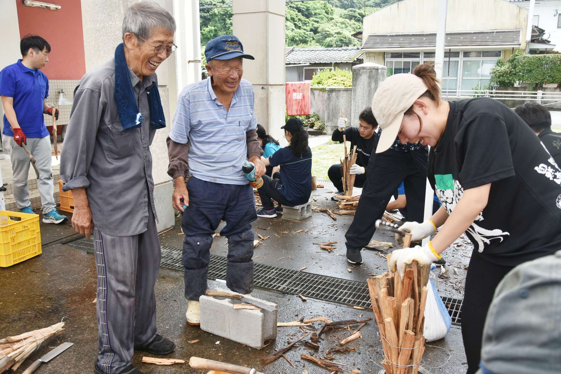 たいまつ作りを楽しむ鹿児島大学の学生（右）＝南大隅町根占山本の宮田小学校跡