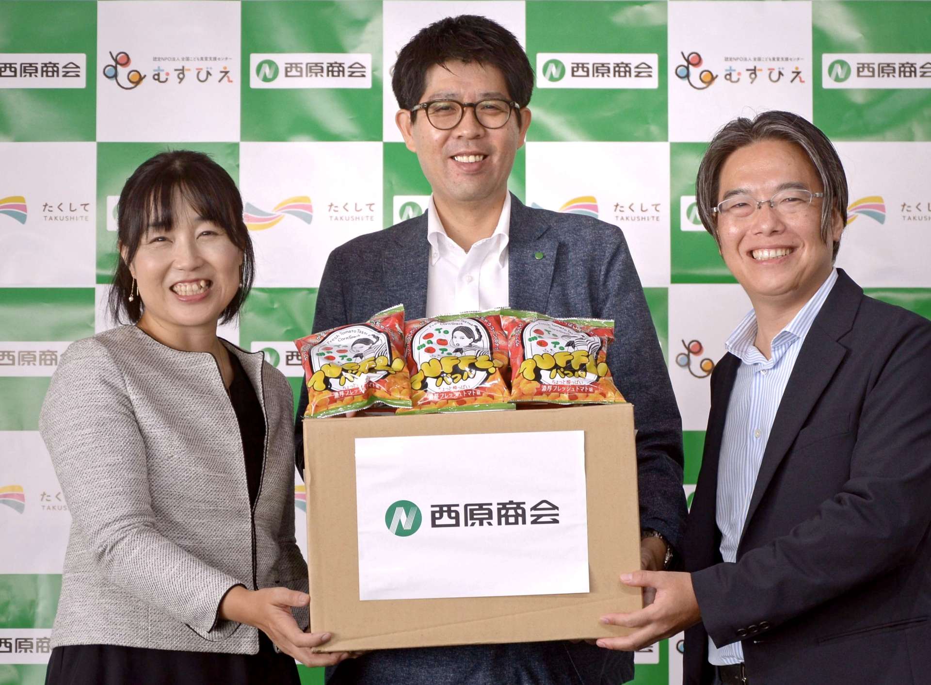 子ども食堂にスナック菓子を贈った西原商会の担当者（中央）ら＝４日、鹿児島市与次郎１丁目の西原商会