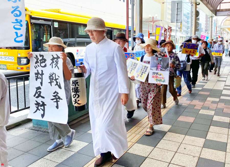 「広島原爆の残り火」を手に天文館を歩く平和巡礼の参加者＝６日、鹿児島市東千石町