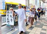 「広島原爆の残り火」を手に天文館を歩く平和巡礼の参加者＝６日、鹿児島市東千石町