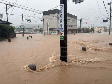 茶色く濁った水に漬かった道路＝８日午前６時５５分ごろ、霧島市国分中央３丁目のＪＲ国分駅付近