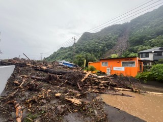 〈あふれる土砂と木々〉上流で河川が決壊し、住宅近くまで土砂が迫る霧島市国分敷根の高橋川付近＝８日午前