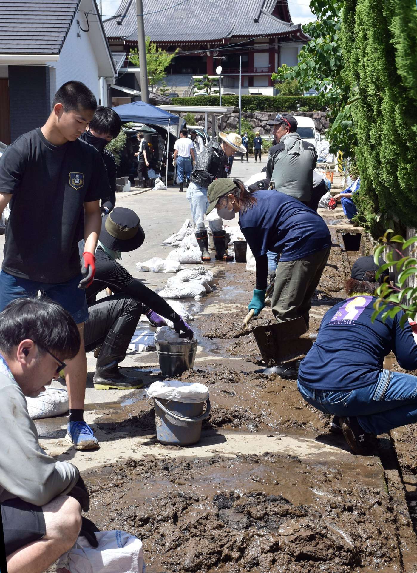 大雨被害を受けた姶良市で側溝に詰まった泥をかき出すボランティアら＝１３日午後１時半