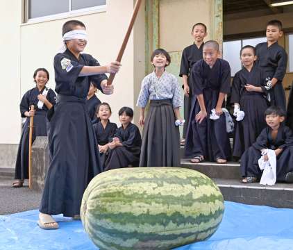 〈割るのに数人がかり…〉９８キロのスイカ割りを楽しむ子どもたち＝南さつま市加世田地頭所町