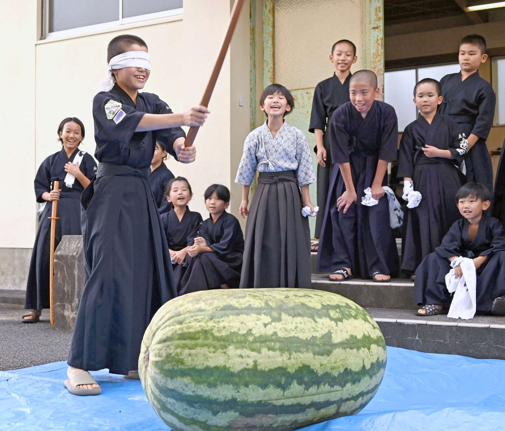 〈割るのに数人がかり…〉９８キロのスイカ割りを楽しむ子どもたち＝南さつま市加世田地頭所町