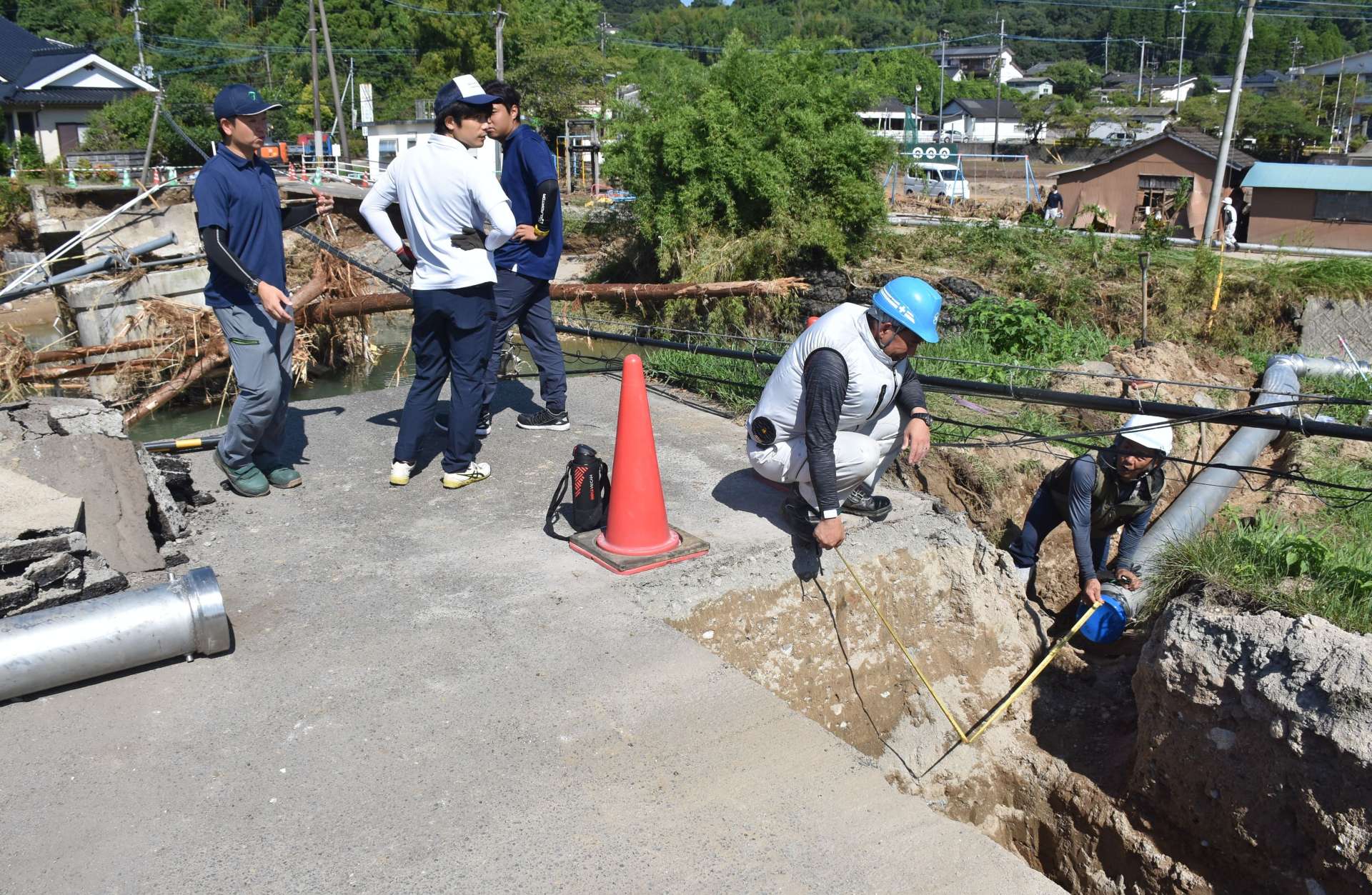 中田橋（左奥）の崩落の影響で損傷した送水管の仮設工事＝１４日、姶良市加治木町小山田