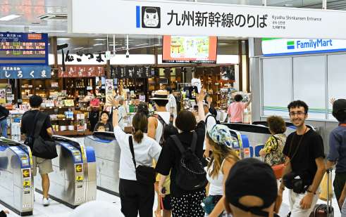 〈最後まで手を振り〉改札口前で別れを惜しむＵターン客＝１６日正午すぎ、鹿児島市のＪＲ鹿児島中央駅