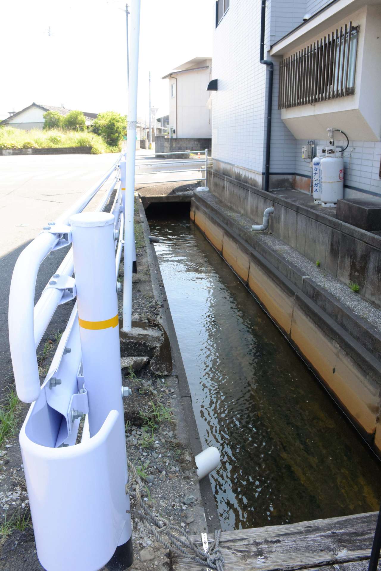 〈幅は１.５メートル〉男性が転落した市道脇の水路。時間帯によっては高温の温泉水が流れる＝１６日、指宿市大牟礼３丁目