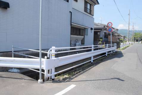 〈周辺は通学路にもなっている〉男性が転落した市道脇の水路。事故後、柵の設置が進む＝１６日、指宿市大牟礼３丁目