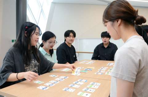地域交通を題材にしたカードゲームを楽しむ志學館大学の学生ら＝鹿児島市の同大