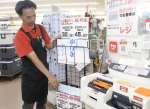 レジ横にばら売りの指定ごみ袋を陳列する店員＝西之表市のサムズ西之表店