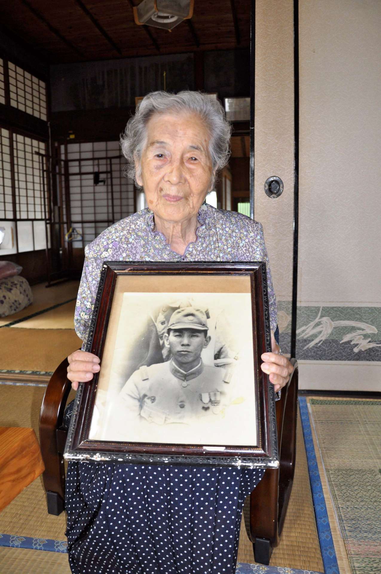 夫・貞喜さんの遺影を手にする池田ナミさん＝出水市野田町下名