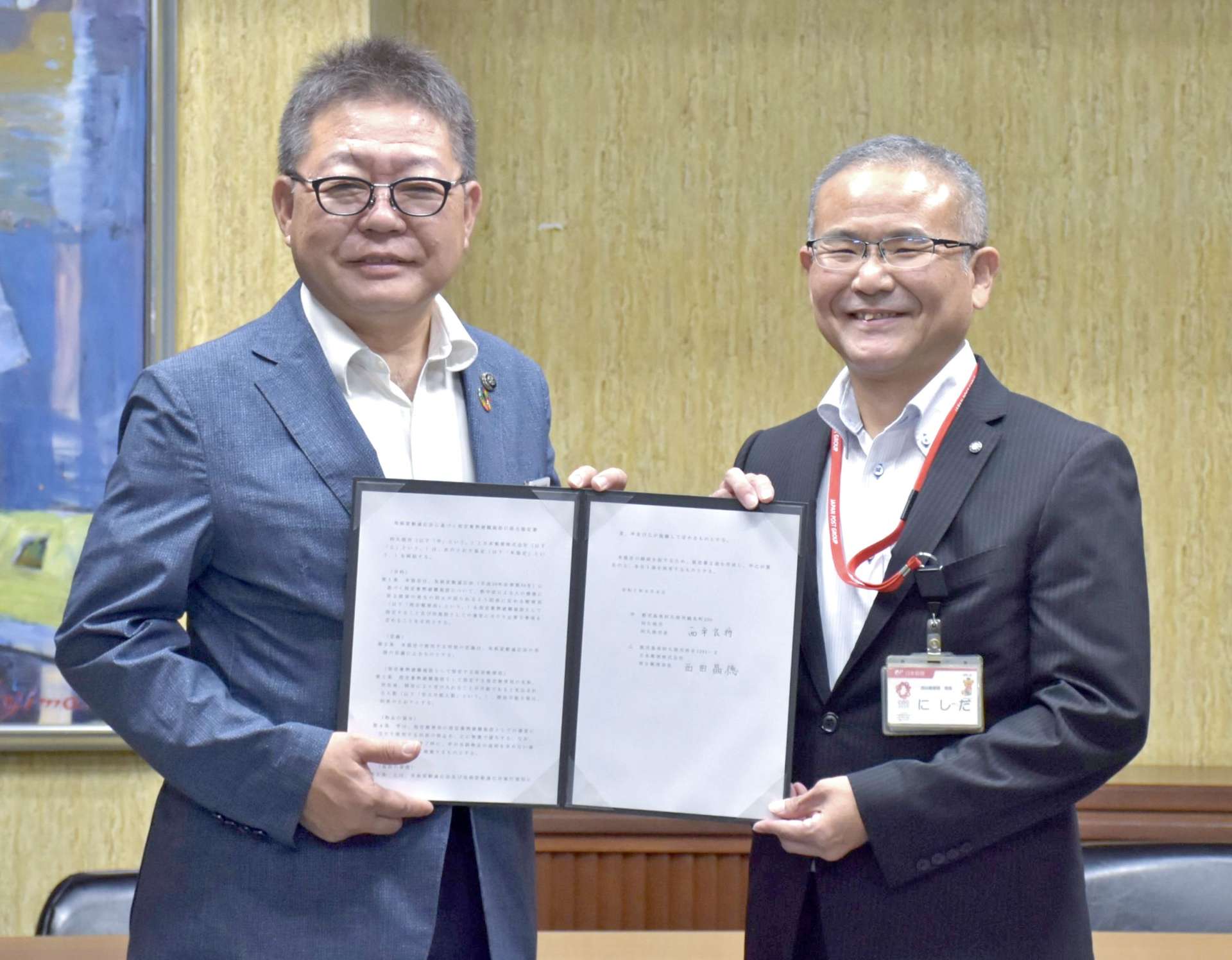 協定書を手にする西平良将市長（左）と西田晶徳・西目郵便局長＝阿久根市役所