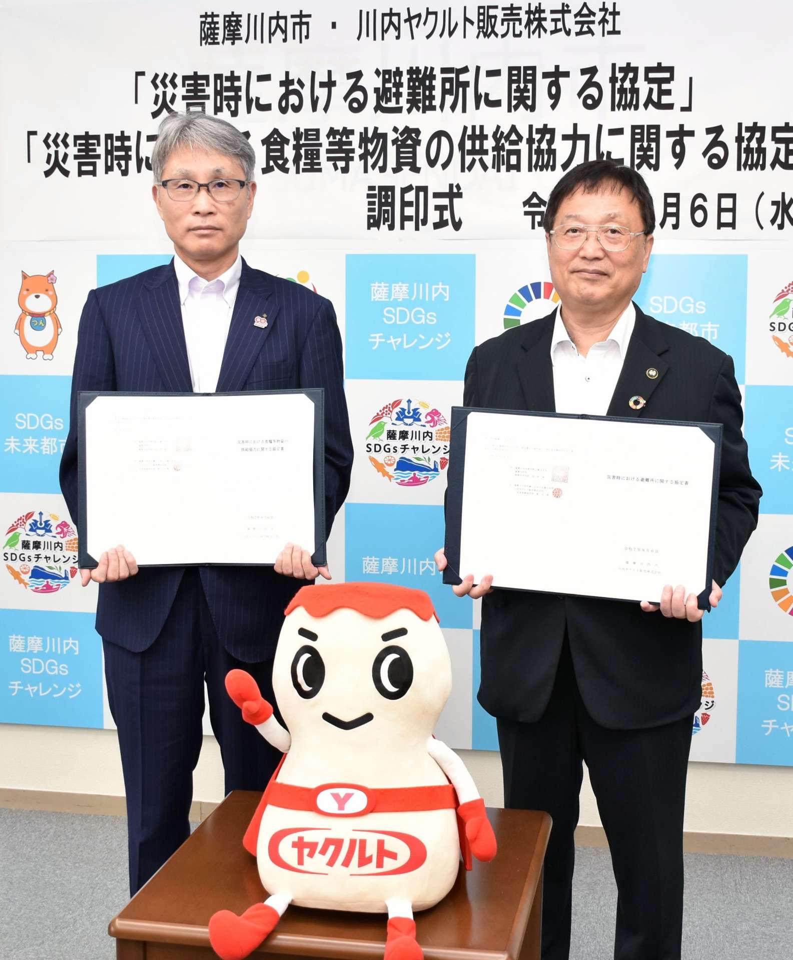協定書を手にする川内ヤクルト販売の影山俊二社長（左）＝薩摩川内市役所